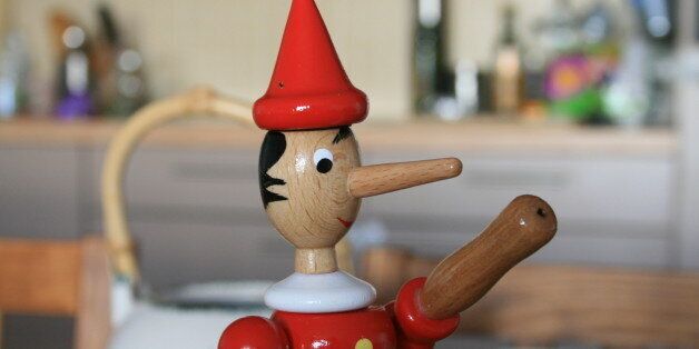 Wooden Pinocchio on the table. Pinocchio is known for having a long nose that becomes longer when he is under stress, especially while telling a lie.