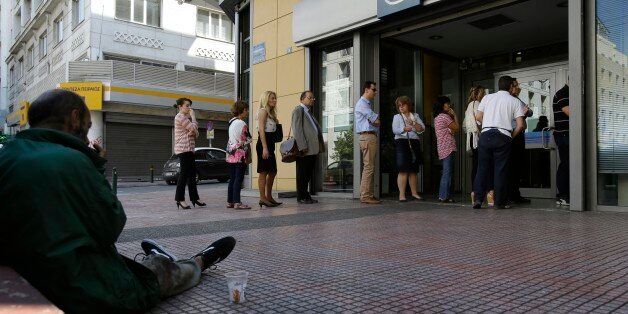 People stand in a queue to use an ATM, as a man begs for money in Athens, Wednesday, July 1, 2015. European officials and Greek opposition parties have been adamant that a
