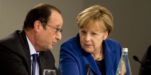 German Chancellor Angela Merkel (R) and French President Francois Hollande chat during a press conference following a European Union (EU) extraordinary summit 'Growth and Employment' on October 8, 2014 in Milan. European Union leaders headed to Milan today for an emergency jobs summit that was set to be overshadowed by a deepening split over the rules governing the euro. Matteo Renzi, Italy's reform-minded young prime minister, called the meeting to kickstart a discussion on balancing budget def