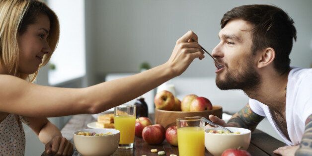 Beautiful girl feeding her boyfriend with spoon, this couple is so contemporary and cute!