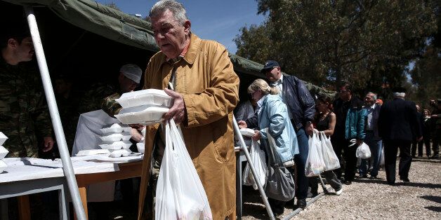 People line up to take a free meal which is distributed at a military camp in Athens, Sunday, April 12, 2015. Greece's Defense ministry organized a meal for the poor on Sunday, a day on which Orthodox Christians around the world celebrate Easter. (AP Photo/Yorgos Karahalis)