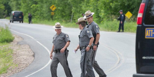 MALONE, NY - JUNE 27: Law enforcement officers walk toward their command center as others guard the perimeter of a wooded area where they believe escaped convict David Sweat may be hiding on June 27, 2015 near Malone, New York. Yesterday Richard Matt, who escaped with Sweat, was shot and killed in the same by area, which is about 8 miles south of the town of Malone. More than 1,000 State Police, Border Patrol, correction officers, FBI and others have been searching for the pair since they were discovered missing from a prison in nearby Dannemora on June 6. (Photo by Scott Olson/Getty Images)
