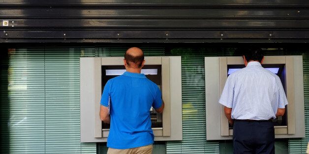 Men use the ATM outside of a closed bank five days before the upcoming referendum, in central Athens, on Tuesday, June 30, 2015. Greek Finance Minister Yanis Varoufakis confirmed that the country will not make its payment due later to the International Monetary Fund. Capital controls began Monday and will last at least a week, an attempt to keep the banks from collapsing in the face of a nationwide bank run. (AP Photo/Petros Karadjias)