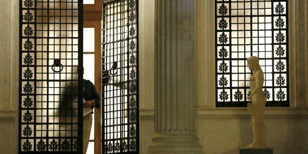 An unidentified man walks out of Maximos Mansion after Greek Prime Minister Alexis Tsipras announced the referendum in a televised address in central Athens, early Saturday, June 27, 2015. Greece's prime minister on Friday called a surprise referendum for July 5 on the financially troubled country's fraught bailout talks with international creditors, and government officials are calling on the nation to reject the proposed deal. (AP Photo/Petros Karadjias)