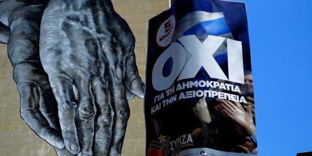 Hands painted on the wall of a building seen behind a poster for a NO vote in the upcoming referendum, in central Athens, Wednesday, July 1, 2015. European officials and Greek opposition parties have been adamant that a