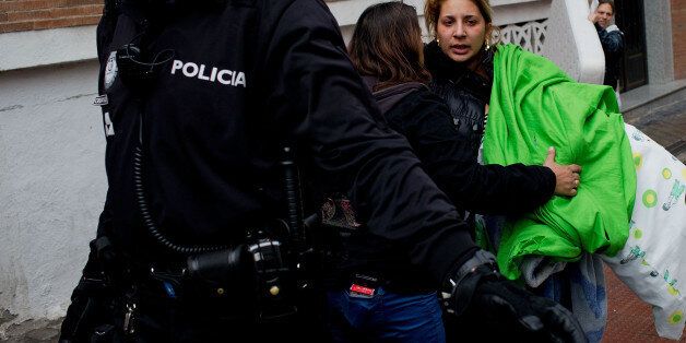 MADRID, SPAIN - NOVEMBER 14: Laura de la Rosa (R) is helped by an activist from the Victims Mortage Platform (PAH) as she carries bags after being evicted on November 14, 2014 in Madrid, Spain. Laura de la Rosa, 30, and her four children are being evicted today after one year illegially occupying, or 'squatting', in a property owned by the Spanish bank, Bankia. Laura supports her family with 530 Euros per month, given as 'Social Wage' aid. This is their second home they have squatted in. Accord