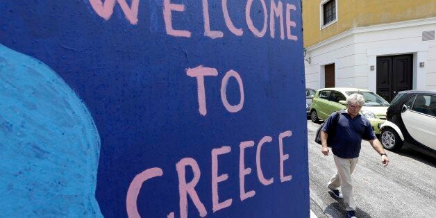 A man passes graffiti in the Plaka tourist district in Athens, Friday, June 5, 2014. Greek Prime Minister Alexis Tsipras is set to address an emergency session of Parliament over the country's struggles to get a deal with creditors, a day after his government opted to delay loan repayments to the International Monetary Fund â a gambit that has rattled markets all around the world (AP Photo/Thanassis Stavrakis)