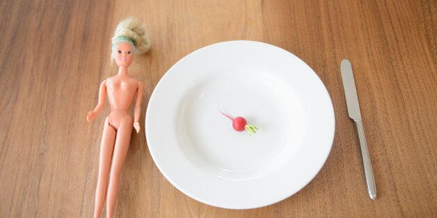 Toy fashion doll next to meal of a radish on plate