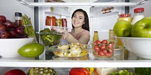 Woman looking at camera out of the fridge.