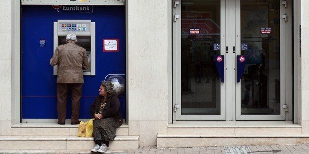 A woman begs for money outside a bank's branch in central Athens on April 6, 2015. Greece has agreed to repay its debt to the International Monetary Fund by April 9, IMF chief Christine Lagarde said after a meeting with Greek Finance Minister Yanis Varoufakis. AFP PHOTO / LOUISA GOULIAMAKI (Photo credit should read LOUISA GOULIAMAKI/AFP/Getty Images)