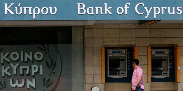 A man passes outside of a branch of bank of Cyprus at a main shopping street in central capital Nicosia, Cyprus, Sunday, April 14, 2013. Cyprus' President Nicos Anastasiades has chided the central bank chief to not act in ways that