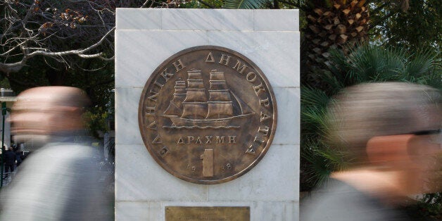 Pedestrians pass a plaque of a Greek one-drachma coin, which was replaced by the euro in 2002, outside Athens City Hall, on Wednesday, Nov. 2, 2011. Greek Prime Minister George Papandreou will try to win over irate European leaders later Wednesday, hours after persuading his cabinet to back a hugely-controversial referendum on the debt-crippled country's latest rescue package. (AP Photo/Thanassis Stavrakis)