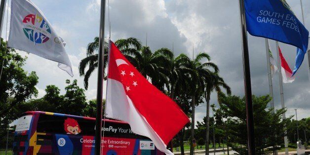 Singapore's national flag (C) is pictured flying at half mast outside the a venue for the 28th Southeast Asian Games (SEA Games) in Singapore on June 8, 2015 as the nation mourns its nationals killed on June 5 in an earthquake on neighbouring Malaysia's Mount Kinabalu. Athletes, officials and fans at Singapore's SEA Games marked a sombre minute's silence on June 8 for the six Singaporean schoolchildren and two adults killed in the earthquake, which killed at least 16 people in total. AFP PHOTO / MOHD FYROL (Photo credit should read MOHD FYROL/AFP/Getty Images)