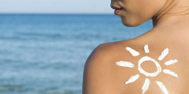 Woman With Suntan Lotion At The Beach In Form Of The Sun.