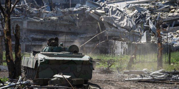 A Russia-backed armoured personnel carrier makes its way near positions at the destroyed building of Donetsk Airport just outside Donetsk, eastern Ukraine, Tuesday, June 9, 2015. Heavy fighting continue at the frontline at the airport of Donetsk. (AP Photo/Mstyslav Chernov)