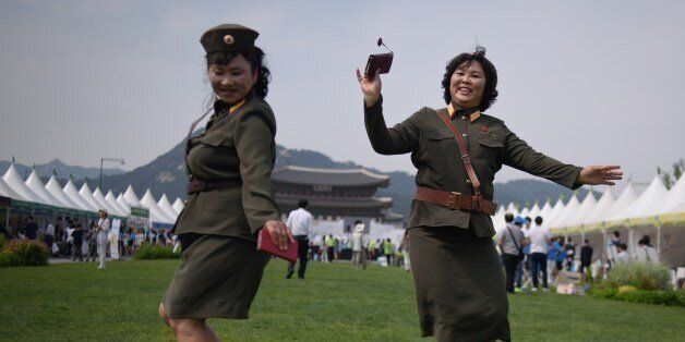 North Korean defectors wearing North Korean military uniforms dance in Gwanghwamun square during a 'unification expo' in central Seoul on May 29, 2015. The expo aims to raise awareness about inter-Korean unification. AFP PHOTO / Ed Jones (Photo credit should read ED JONES/AFP/Getty Images)