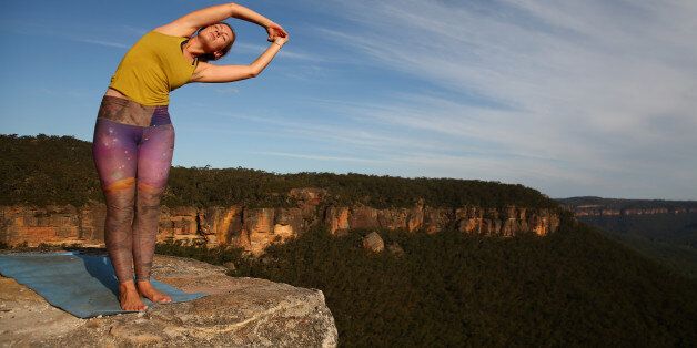 MT VICTORIA, AUSTRALIA - MARCH 07: Thea Bainbridge of England practices yoga on the cliffs at Corroboree Walls in Mount Victoria on March 7, 2015 in the Blue Mountains, Australia. On March 6th 8th the highlining community from around the world ascended on Mount Victoria in the Blue Mountains two hours west of Sydney for a weekend of challenging lines and routes established between various cliffs in the mountains. Seven highlines of different spans and tension were rigged and participants of various skill levels and experience challenged themselves. The crowd that gathered shared a similar passion for adventure, the outdoors and relaxing together sharing stories and encouraging each other as they push their limits in the stunning Blue Mountains National Park. Growing in popularity the relatively new sport seems dangerous and extreme, however safety is paramount with numerous safety harnesses and procedures are implemented to maintain a well measured and safe environment. Slacklining is a balance sport in which participants walk on a flat nylon webbing anchored between two points with the tension adjusted to allow for slack, providing an experience similar to that of walking on a trampoline. Highlining is a style of slacklining where the two anchor points are set up with significant elevation from the ground or water below known as exposure. Unlike extreme sports such as skydiving or bungee jumping, the participant has to make constant decisions and mentally overcome their fear and harness their adrenalin compared to making that one initial choice to jump in the case of the other sports. Numerous highliners are confident walking a slackline of the same distance in a park low to the ground, however the mental challenge at heights with the view below and environmental elements to contend with proves a much tougher challenge. (Photo by Cameron Spencer/Getty Images)