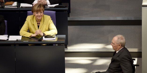 German Finance Minister Wolfgang Schaeuble (R) passes on his wheelchair by German Chancellor Angela Merkel (L) after addressing the lower house of Parliament Bundestag in Berlin on February 27, 2015 before Germany's parliament vote on the approval of the four-month-extension of the Greek bail-out programme despite widespread scepticism in Europe's biggest economy and effective paymaster on whether Athens will stick to reform pledges. (Photo credit should read ODD ANDERSEN/AFP/Getty Images)