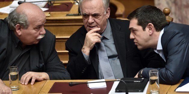 Greek Prime Minister Alexis Tsipras (R), Deputy Prime Minister Yannis Dragasakis (C) and Interior Minister Nikos Voutsis speak as they attend a parliament session in Athens on March 30, 2015. The EU warned Monday that Greece and its creditors had yet to hammer out a new list of reforms despite talks lasting all weekend aimed at staving off bankruptcy and a euro exit. AFP PHOTO / ARIS MESSINIS (Photo credit should read ARIS MESSINIS/AFP/Getty Images)