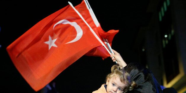 A supporters of Turkey's ruling Justice and Development Party holds a baby as she waves Turkish flags in Istanbul,Turkey, late Sunday, June 7, 2015. With 99.9 percent of the vote counted, President Recep Tayyip Erdogan's AKP had the support of around 41 percent of voters, state-run TRT television said. The unexpected setback for AKP likely puts an end, for the time being, to Erdogan's hopes of passing constitutional changes that would have greatly boosted the powers of his office. Instead, he fa