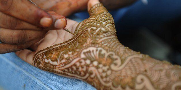 An Indian Muslim woman gets her hands decorated with traditional henna designs at a roadside stall ahead of the Muslim festivities of Eid al-Fitr, in Mumbai on July 28, 2014. Muslims around the world are preparing to celebrate the Eid al-Fitr holiday, which marks the end of the fasting month of Ramadan. AFP PHOTO/ INDRANIL MUKHERJEE (Photo credit should read INDRANIL MUKHERJEE/AFP/Getty Images)