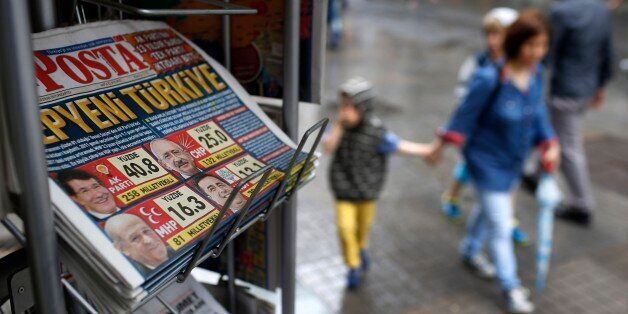 People walk past a kiosk with newspapers featuring front-page coverage of Sunday's elections, in Istanbul, Turkey, Monday, June 8, 2015. Turkeyâs long-ruling party has suffered surprisingly strong losses in parliament that will force it to seek a coalition partner for the next government, but other parties vowed to resist any pact as election results flowed in Monday. President Recep Tayyip Erdogan's Justice and Development Party, known as the AKP, won less than 41 percent of votes in Sunday's election for Turkeyâs 550-seat parliament. It was projected to take 258 seats, still top of the political heap but 18 below the minimum required to rule alone. (AP Photo/Emrah Gurel)