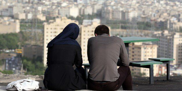TO GO WITH AFP STORY BY ARTHUR MACMILLANAn Iranian couple sit together in the northwestern Shahran neighbourhood overlooking Tehran on June 7, 2014. One in three marriages fails in the Iranian capital; in its northern quarter, home to the more affluent Western-leaning metropolitan elite, the figure is more than 40 percent. AFP PHOTO/ATTA KENARE (Photo credit should read ATTA KENARE/AFP/Getty Images)