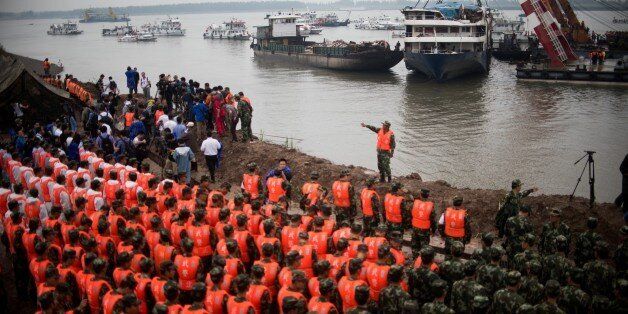 Chinese soldiers and rescue workers pay there respect to the victims during a memorial service in front of the raised Chinese cruise ship, in Jianli on June 7, 2015. Rescuers extended their search for victims of a Chinese cruise ship sinking to include a vast stretch of the Yangtze river Saturday, as the confirmed death toll rose to 396, marking the country's worst shipping disaster in nearly 70 years. AFP PHOTO / JOHANNES EISELE (Photo credit should read JOHANNES EISELE/AFP/Getty Images)