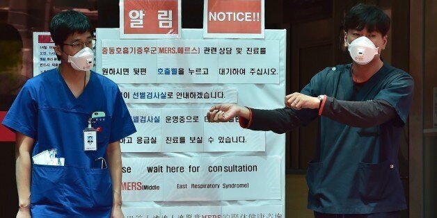 South Korean hospital workers wearing masks stand in front of a public notice on MERS while setting up a separated emergency center at the National Medical Center in Seoul on June 1, 2015. South Korean President Park Geun-Hye scolded health officials on June 1, over their response to an outbreak of the MERS virus, as the number of infections climbed to 18, with nearly 700 under observation. Major South Korean hospitals are setting up special MERS clinic rooms to fight the disease. AFP PHOTO / JUNG YEON-JE (Photo credit should read JUNG YEON-JE/AFP/Getty Images)