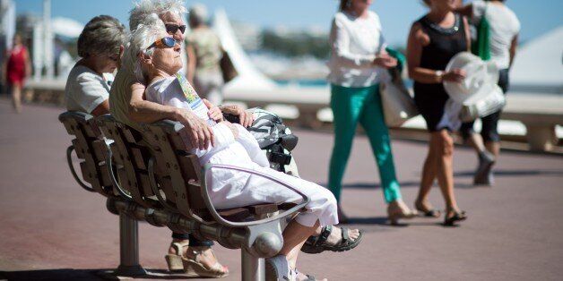 An elderly couple sit on a bench on the Croisette during the 68th Cannes Film Festival in Cannes, southeastern France, on May 20, 2015. AFP PHOTO / BERTRAND LANGLOIS (Photo credit should read BERTRAND LANGLOIS/AFP/Getty Images)