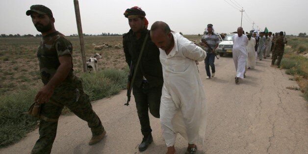 Iraqi pro-government militiamen escort men they detain for investigation after the liberation from Islamic State (IS) militants of the village of Sayed Ghareeb, near Dujail, some 70 kilometres north of Baghdad on June 2, 2015. AFP PHOTO / MOHAMMED SAWAF (Photo credit should read MOHAMMED SAWAF/AFP/Getty Images)