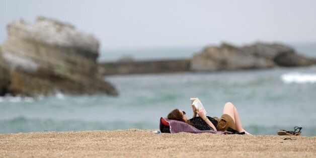 A woman reads a book on the beach in Biarritz on April 15, 2015. AFP PHOTO / GAIZKA IROZ (Photo credit should read IROZ GAIZKA/AFP/Getty Images)