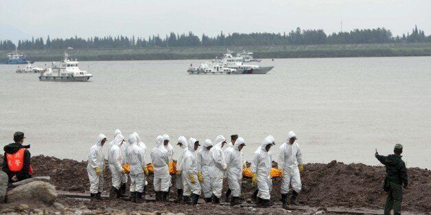This picture taken on June 3, 2015 shows Chinese rescue workers removing the bodies of victims from the Chinese cruise ship which capsized three days ago in the Yangtze river in Jianli, in central China's Hubei province. Hundreds of relatives of passengers missing after their cruise ship capsized in central China gathered at the disaster site on June 4, as rescuers breached the hull in a last-ditch search for more than 400 people believed trapped inside. CHINA OUT -- AFP PHOTO (Photo c