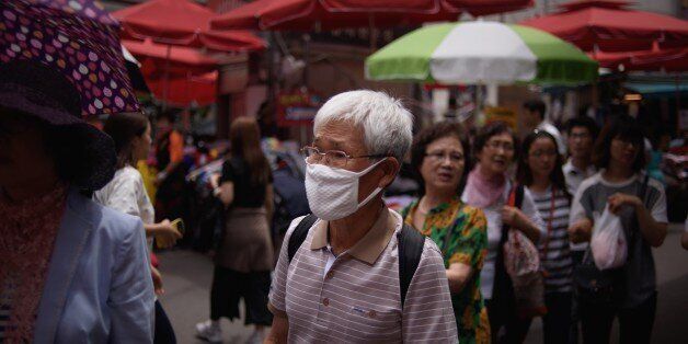 A man wearing a face mask walks through a market in Seoul on June 1, 2015. South Korean President Park Geun-Hye scolded health officials over their 'insufficient' response to an outbreak of the MERS virus, as the number of infections climbed to 18, with nearly 700 under observation. AFP PHOTO / Ed Jones (Photo credit should read ED JONES/AFP/Getty Images)