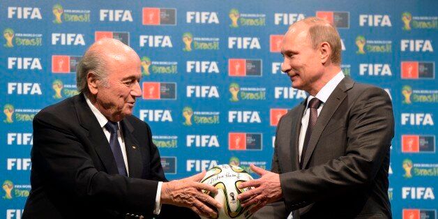 FILE - In this file photo taken on Sunday, July 13, 2014, FIFA President Sepp Blatter, left, and Russian President Vladimir Putin hold a soccer ball during the official ceremony of handover to Russia as the 2018 World Cup hosts, after the World Cup final soccer match between Germany and Argentina at the Maracana Stadium in Rio de Janeiro. Russian football is plagued by a racist and far-right extremist fan culture that threatens the safety of visitors to the 2018 World Cup, a dossier provided to The Associated Press revealed on Friday, Feb. 27, 2015. Researchers from the Moscow-based SOVA Center and the Fare network, which helps to prosecute racism cases for UEFA, cataloged more than 200 cases of discriminatory behavior linked to Russian football across two seasons.(AP Photo/RIA-Novosti, Alexei Nikolsky, Presidential Press Service, File)