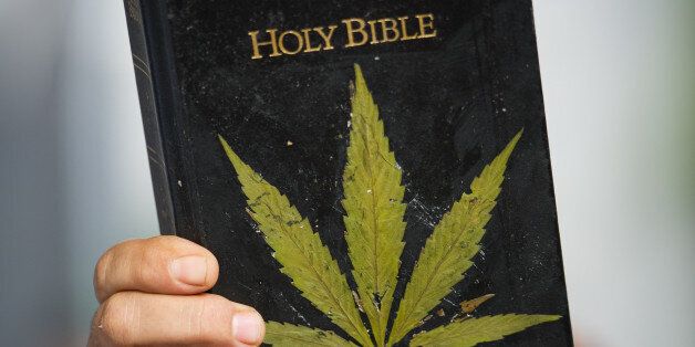 A man holds a Bible with leaves pasted on the cover simulating a marijuana plant during a demo for its legalization in Sao Paulo, Brazil, on May 19, 2012. AFP PHOTO/Yasuyoshi CHIBA (Photo credit should read YASUYOSHI CHIBA/AFP/GettyImages)