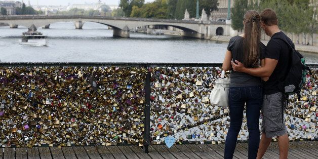TO GO WITH AFP STORY BY BONIFACE MURUTAMPUNZIA couple looks at the Pont des Arts where padlocks are attached to the railing, on August 30, 2013 in Paris. Due to security reason authorities consider removing the 'Love locks' that have been attached to the Pont des Arts bridge since 2008 by thousand of lovers.AFP PHOTO / PATRICK KOVARIK (Photo credit should read PATRICK KOVARIK/AFP/Getty Images)