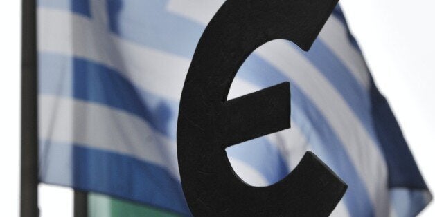 The Greek flag flies behind a statue of the euro sign in front of the European Parliament in Brussels on July 19, 2012. Eurozone finance ministers will hold a teleconference on July 20 to finalise a Spanish bank bailout deal, Luxembourg prime minister and Eurozone President Jean-Claude Juncker said. Eurozone governments have pledged an aid package of up to 100 billion euros ($122 billion) for Spain's debt-mired bank sector.AFP PHOTO/GEORGES GOBET (Photo credit should read GEORGES GOBET/AF