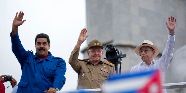 Venezuelan President Nicolas Maduro, from left to right, Cuba's President Raul Castro, and Cuba's First Vice President of the Council of State Jose Ramon Machado Ventura, wave as they watch the May Day parade at Revolution Square, in Havana, Cuba, Friday, May 1, 2015. Thousands of people converged on the plaza despite the rain for the traditional march. (AP Photo/Ramon Espinosa)
