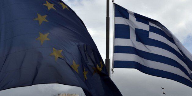A Greek and an EU flag wave in front of the ancient temple of Parthenon atop the Acropolis hill in Athens on January 13, 2015. Greece could exit the euro by accident, Finance Minister Gikas Hardouvelis said Wednesday in a new warning of what could happen if anti-austerity leftist party Syriza wins the election later this month. AFP PHOTO / ARIS MESSINIS (Photo credit should read ARIS MESSINIS/AFP/Getty Images)