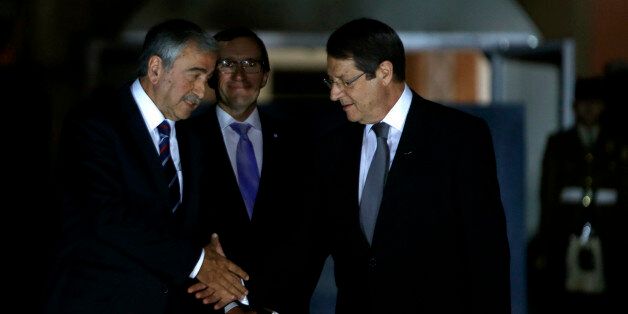 Cyprus' president Nicos Anastasiades, right, shakes hands with Turkish Cypriot leader Mustafa Akinci as the United Nations envoy Espen Barth Eide, center, looks on before a dinner at the Ledra Palace Hotel inside the UN controlled buffer zone that divides the Cypriot capital Nicosia, on Monday, May 11, 2015. The dinner is the first meeting between Anastasiades and Akinci since the Turkish Cypriot politician _ a left-wing moderate _ soundly defeated the hard-line incumbent in an election last month. Cyprus was split in 1974 when Turkey invaded after a coup by supporters of union with Greece. (AP Photo/Petros Karadjias)