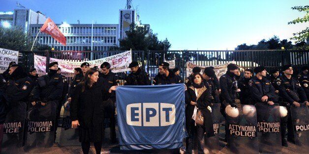 Former ERT employees hold a banner in front of the former state broadcaster's heaquarters in an northern Athens suburb on November 7, 2013 during a demonstration by worker's unions after Greek riot police burst in early morning .Greek riot police stormed the headquarters of former public broadcaster ERT in a pre-dawn raid on Thursday, forcibly removing employees who had been occupying the site since its shock shutdown five months ago.ERT's closure in June sparked an international outcry and