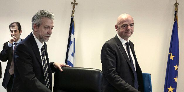 Greece's deputy minister for sport Stavros Kontonis, left, and visiting UEFA General Secretary Gianni Infantino take their seats for a meeting in Athens, on Wednesday, April 29, 2015. Infantino is in Greece meeting lawmakers and sporting officials to try to end a soccer dispute that could trigger the country's international suspension. (AP Photo/Yorgos Karahalis)