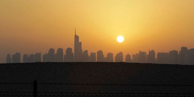 The sun sets behind the city skyline at the Marina district as the Almas tower is seen in Dubai, United Arab Emirates, Friday, March 7, 2014. (AP Photo/Kamran Jebreili)