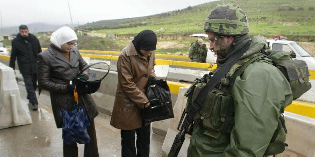 NABLUS, -: An Israeli soldier checks Palestinians at a crossing point near the West Bank city of Nablus, 08 February 2005. Israeli Prime Minister Ariel Sharon and Palestinian leader Mahmud Abbas announced the end of four years of violence at a landmark summit in Egypt, setting the stage for a full-scale revival of the peace process. AFP PHOTO/JAAFAR ASHTIYEH (Photo credit should read JAAFAR ASHTIYEH/AFP/Getty Images)