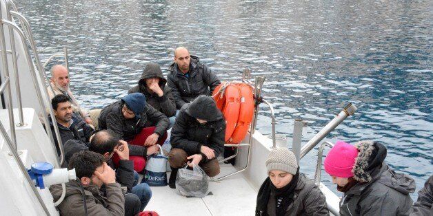 In this Sunday, Jan. 19, 2014 photo immigrants believed to be Syrians sit on a Greek Coast Guard vessel after being detained by Greek authorities in the southeastern island of Symi. In another incident near the eastern Aegean sea near Farmakonissi islet on Monday, Jan. 20, 2014, Greek rescuers are seeking 12 people reported missing after a fishing boat packed with immigrants that was being towed to the shore by a coastguard vessel capsized in the dark. A Merchant Marine Ministry statement says another 16 people were rescued and their nationalities were unknown. (AP Photo/Nikolas Nanev)