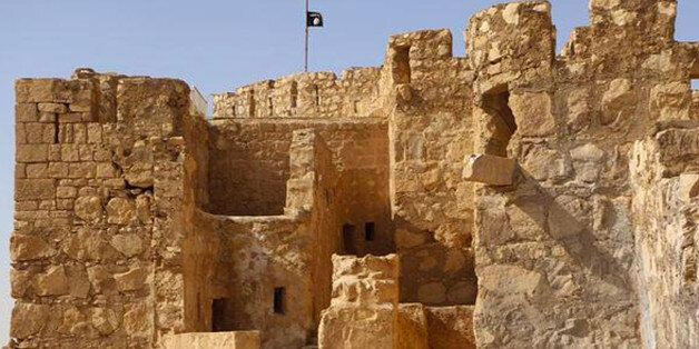 In this picture released on Friday, May 22, 2015 by the website of Islamic State militants, shows the Islamic State militants flag, top center, raised on the to top of Palmyra castle, in the Syrian town of Palmyra, Syria. A Syrian official in charge of antiquities says Islamic State fighters have broken into the museum of the ancient town of Palmyra which they have captured days earlier, but have not harmed its contents. (The website of Islamic State militants via AP)