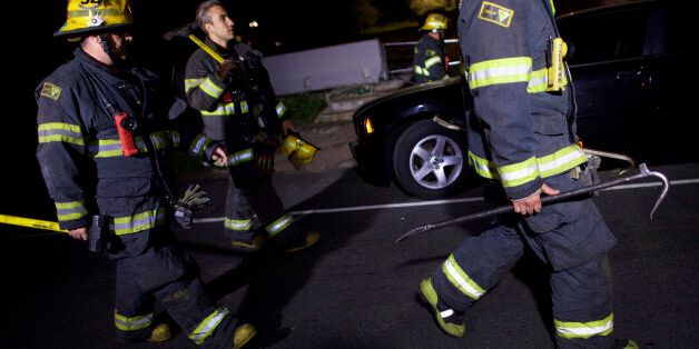 PHILADELPHIA, PA - MAY 13: Fire fighters carry tools back to their truck in the early hours after working at the wreckage of an Amtrak passenger train that derailed carrying more than 200 passengers from Washington, DC to New York on May 13, 2015 in north Philadelphia, Pennsylvania. At least five people were killed and more than 50 others were injured in the crash. (Photo by Mark Makela/Getty Images)