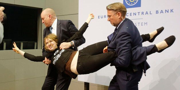 A Femen activist is carried away after attacking ECB President Mario Draghi during a press conference of the European Central Bank, ECB, in Frankfurt, Germany, Wednesday, April 15, 2015. (AP Photo/Michael Probst)