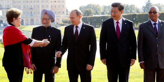 FILE - In this Sept. 5, 2013 file photo, from left, Brazil's President Dilma Rousseff gestures to then Indian Prime Minister Manmohan Singh, Russia's President Vladimir Putin, China's President Xi Jinping and South African President Jacob Zuma, as they gather for a group photo after a BRICS leaders' meeting at the G-20 Summit in St. Petersburg, Russia. In another sign of the shifting balance of power in the world economy, emerging market powers Brazil, Russia, India, China and South Africa are launching a $100 billion development bank to challenge the U.S.-dominated World Bank and help finance $4.5 trillion worth of infrastructure projects. (AP Photo/Sergei Karpukhin, Pool, File)